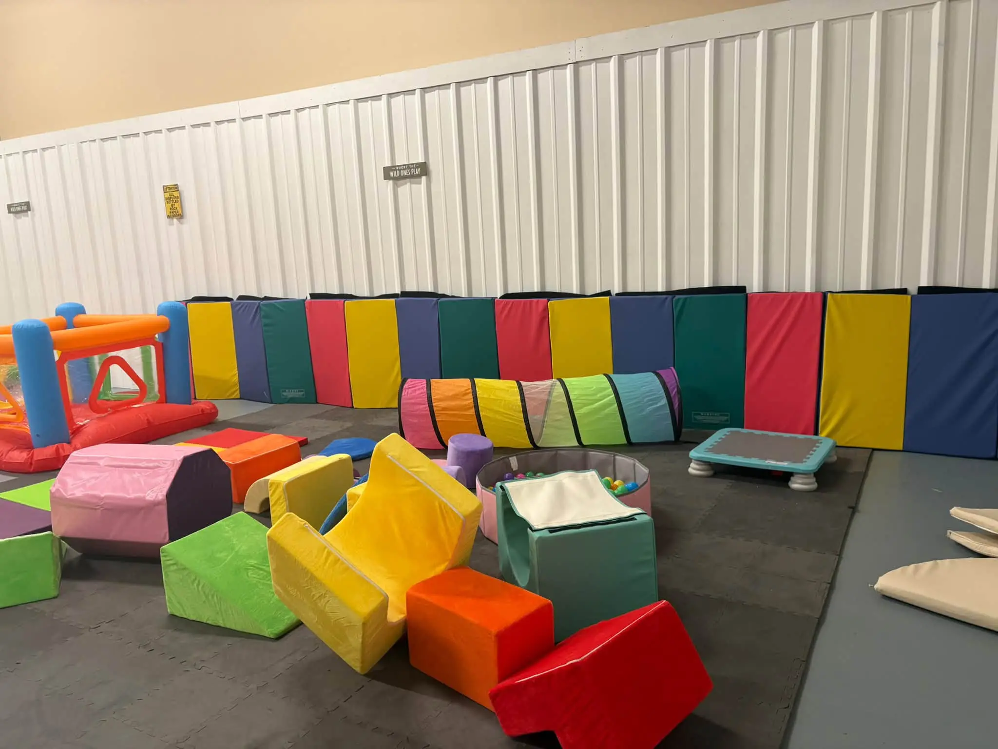 Room filled with lots of colorful soft play equipment, including a variety of soft play mats, pillows