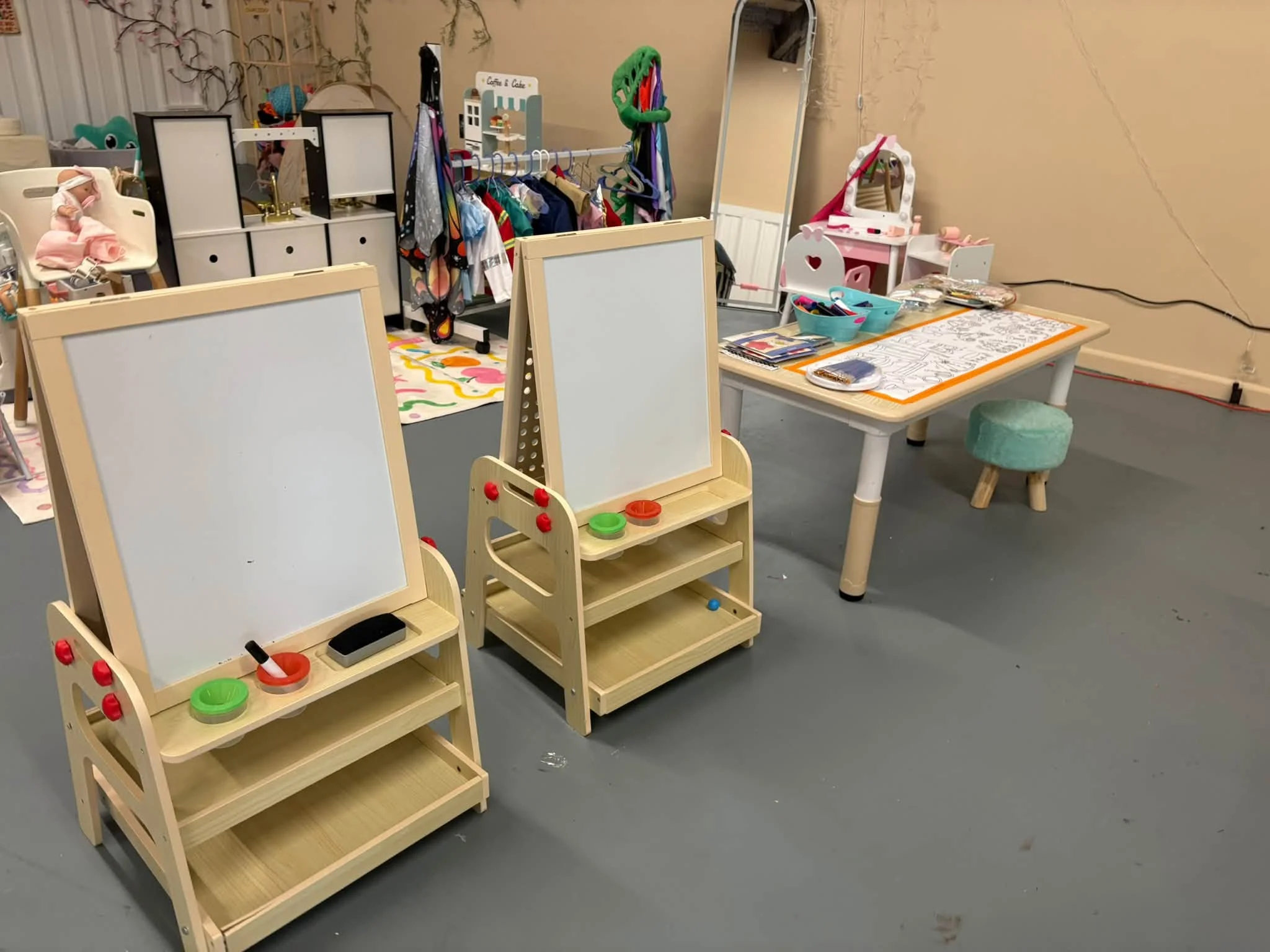 Room filled with lots of different types of art supplies, including a table with a stool, a whiteboard